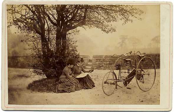 ca. 1870-1900, cabinet card, outdoor portrait of two women reading a map against a tree, with an unusual tandem tricycle parked nearby via www.stereographica.com/auctionframe.html